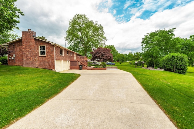 view of home's exterior with a chimney, a lawn, a garage, brick siding, and concrete driveway
