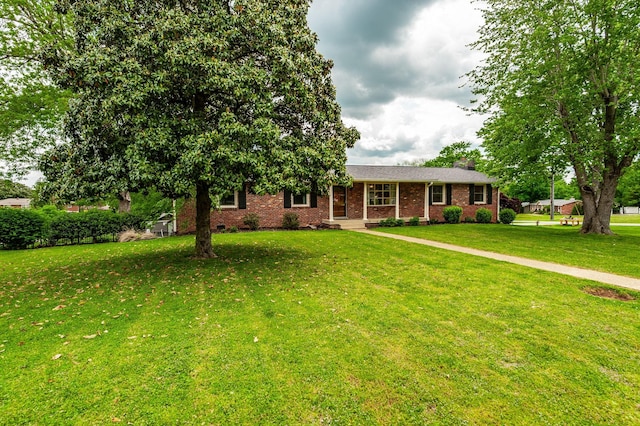 ranch-style home with brick siding, a chimney, and a front lawn