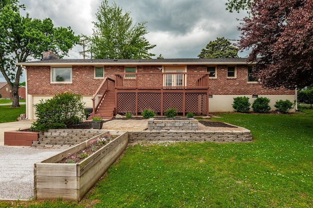rear view of house featuring brick siding, a garage, a wooden deck, a vegetable garden, and a lawn
