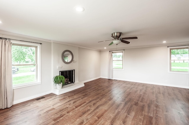 unfurnished living room with visible vents, ornamental molding, a wealth of natural light, and wood finished floors