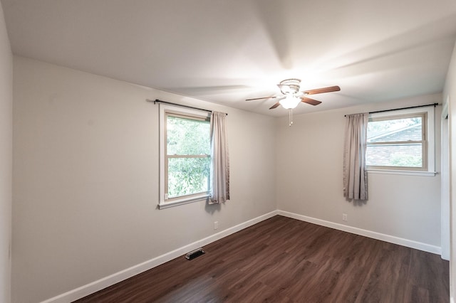 unfurnished room with a ceiling fan, baseboards, visible vents, and dark wood finished floors