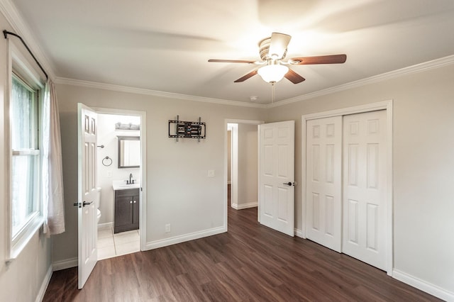 unfurnished bedroom featuring a sink, baseboards, multiple windows, and dark wood-style floors