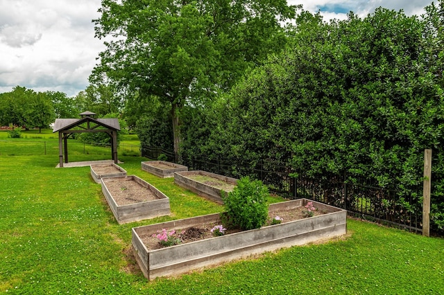 view of community featuring a lawn, fence, a gazebo, and a garden