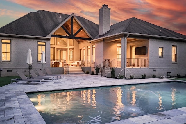 9710 Onyx Ln, Brentwood, TN 37027 - back of house at dusk with stairway, a chimney, an outdoor pool, and a patio area