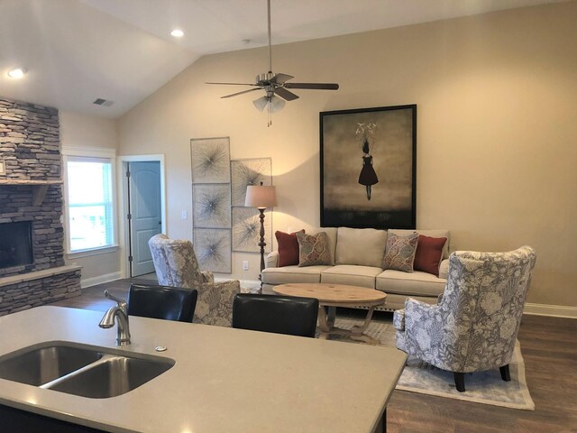 living area with visible vents, baseboards, dark wood-style flooring, a fireplace, and a ceiling fan