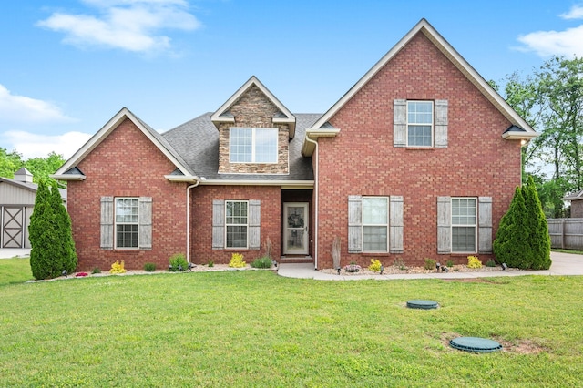 view of front of home with brick siding, fence, a shingled roof, and a front yard