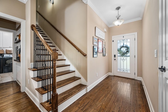 foyer entrance featuring crown molding, dark wood-style flooring, baseboards, washer and clothes dryer, and stairway