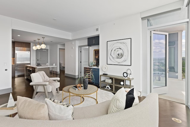 living area featuring baseboards, visible vents, a notable chandelier, and dark wood-type flooring