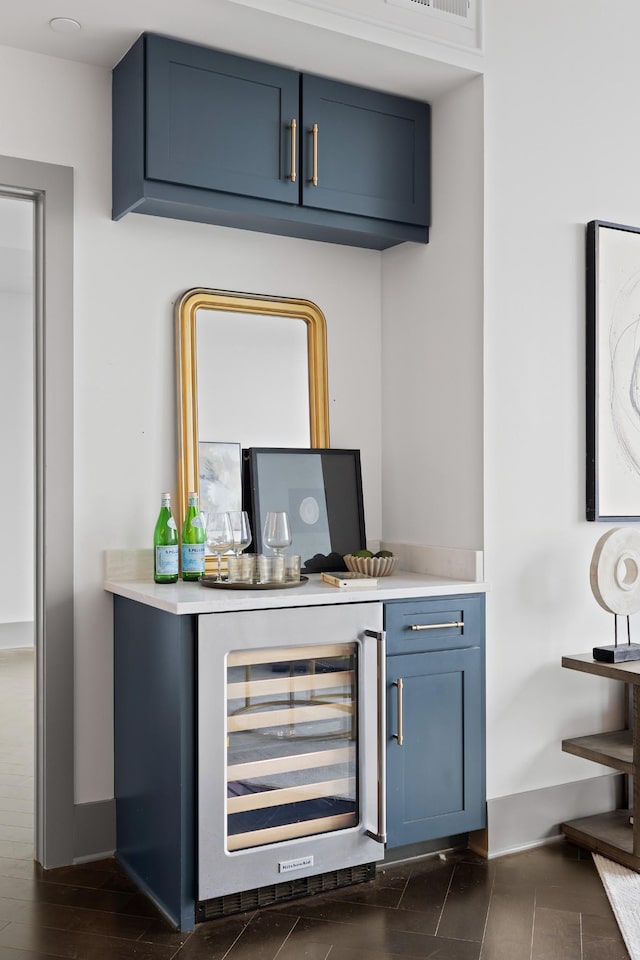 bar featuring wine cooler, baseboards, and a bar