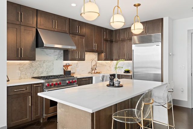 kitchen with dark brown cabinets, light countertops, ventilation hood, backsplash, and premium appliances