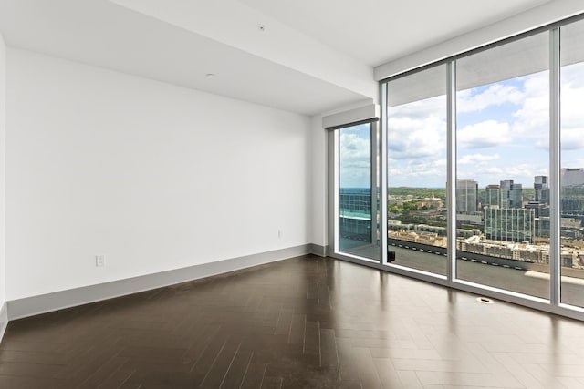 spare room with baseboards, floor to ceiling windows, and a city view