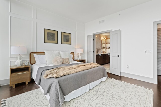 bedroom featuring ensuite bathroom, wood finished floors, and visible vents