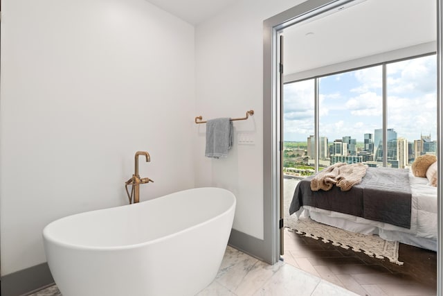 ensuite bathroom featuring a freestanding bath, baseboards, a city view, and ensuite bath