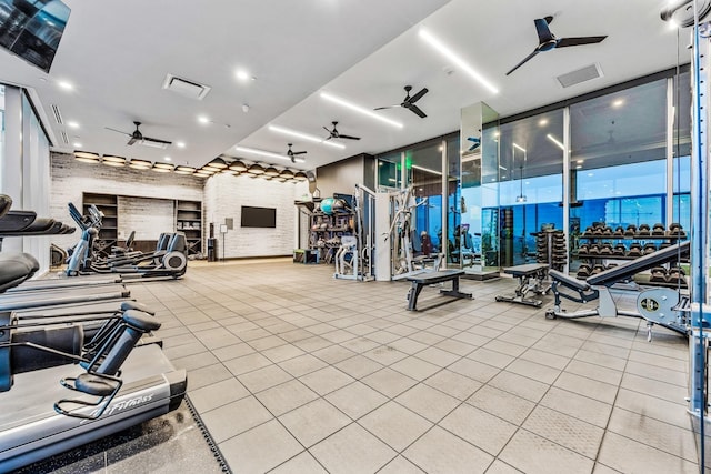 exercise room featuring a wall of windows, a ceiling fan, brick wall, and visible vents