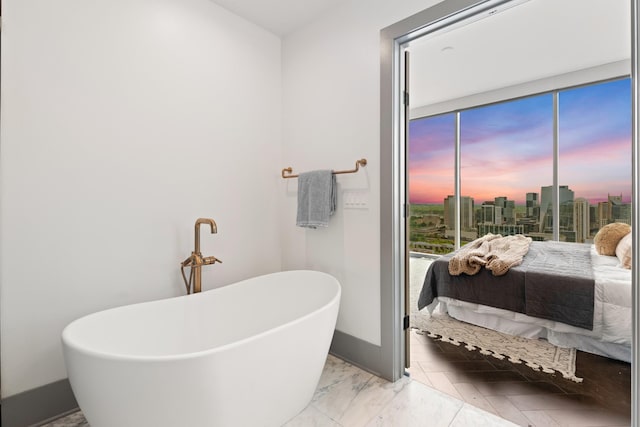 ensuite bathroom with baseboards, a freestanding bath, and ensuite bath