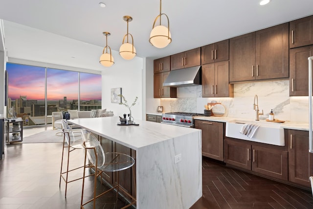 kitchen featuring a center island, light countertops, under cabinet range hood, a sink, and backsplash