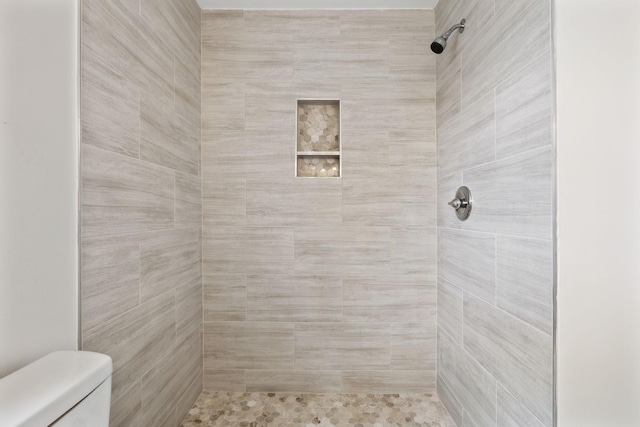 bathroom featuring a tile shower and toilet