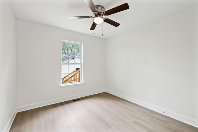 empty room with baseboards, visible vents, wood finished floors, and a ceiling fan
