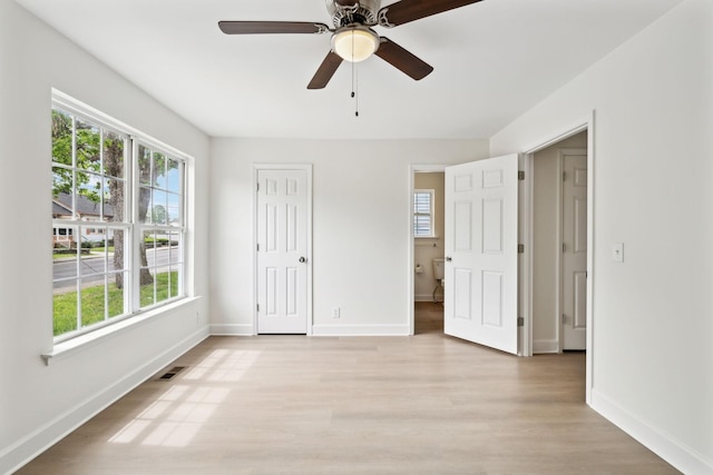 unfurnished bedroom with light wood-type flooring, a ceiling fan, visible vents, and baseboards