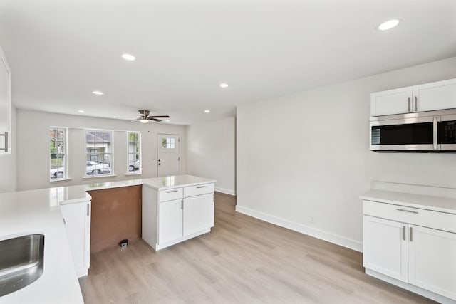 kitchen with stainless steel microwave, recessed lighting, ceiling fan, light wood-type flooring, and white cabinets