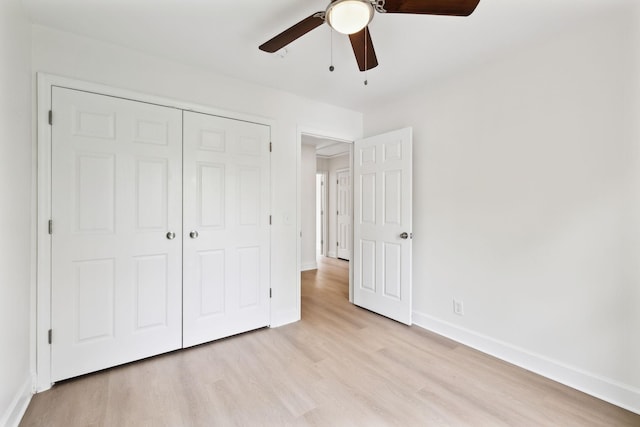 unfurnished bedroom featuring light wood-type flooring, a closet, a ceiling fan, and baseboards