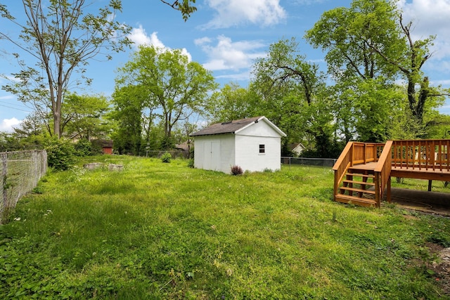 view of yard with an outbuilding, a shed, a deck, and a fenced backyard