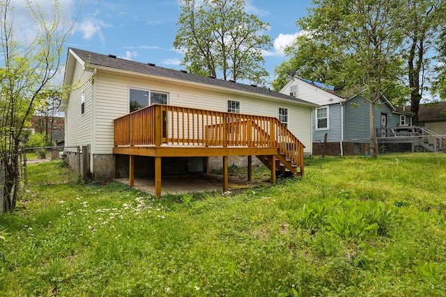 back of property with a deck, stairway, fence, and a lawn