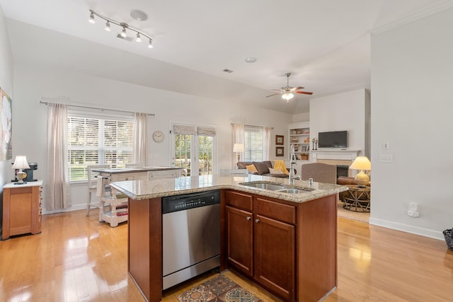 kitchen with stainless steel dishwasher, a sink, light wood-style floors, and open floor plan