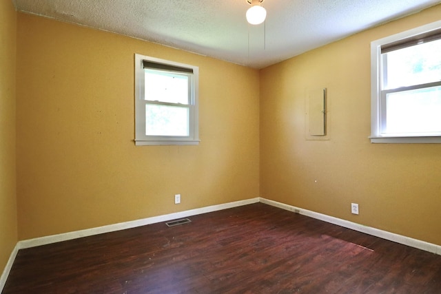 spare room featuring a textured ceiling, visible vents, dark wood finished floors, and baseboards