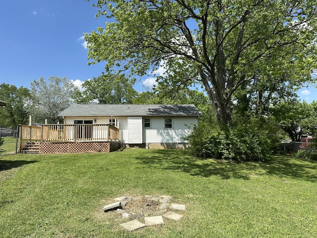 rear view of property featuring fence, a wooden deck, and a lawn