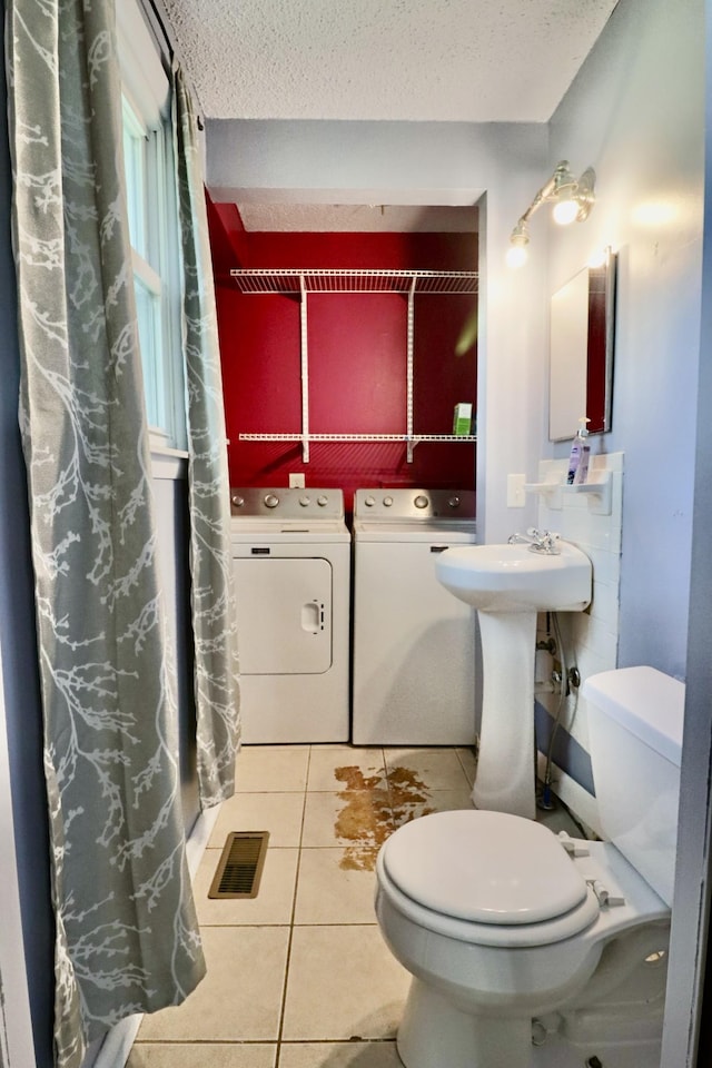 full bath with a textured ceiling, visible vents, toilet, washer and clothes dryer, and tile patterned flooring