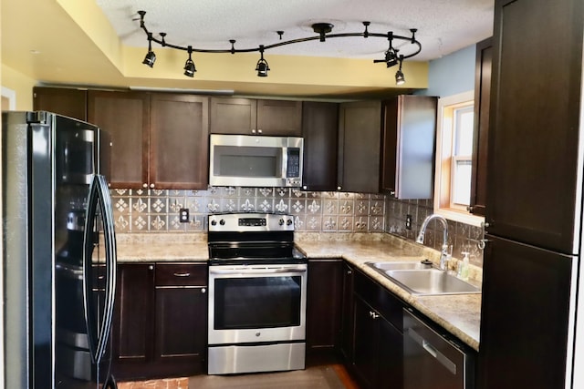 kitchen with appliances with stainless steel finishes, light countertops, decorative backsplash, and a sink
