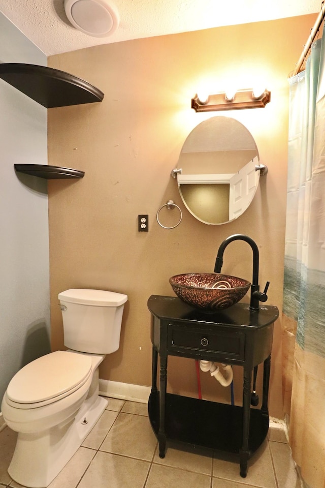 bathroom featuring tile patterned flooring, a shower with shower curtain, toilet, vanity, and a textured ceiling