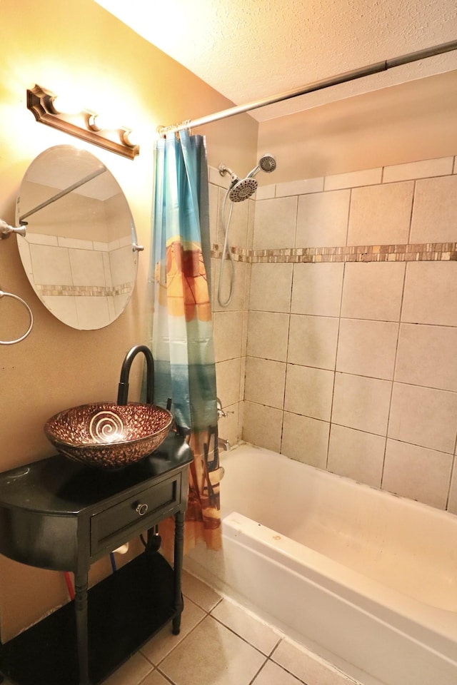 bathroom featuring tile patterned floors, a textured ceiling, shower / bath combination with curtain, and a sink