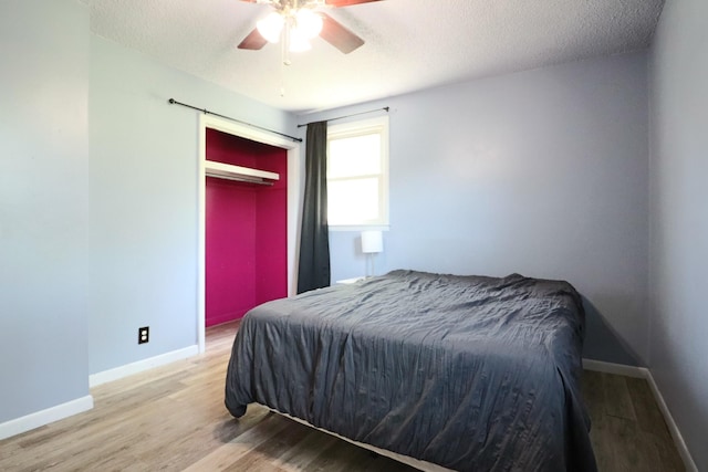 bedroom featuring baseboards, wood finished floors, a ceiling fan, and a textured ceiling