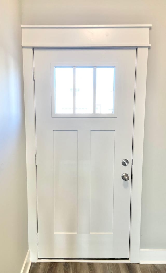 doorway featuring baseboards and wood finished floors