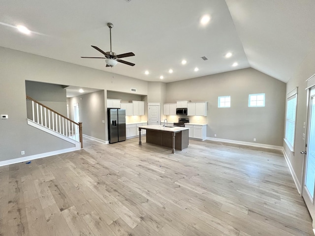 kitchen with open floor plan, light wood-style floors, stainless steel appliances, and a ceiling fan