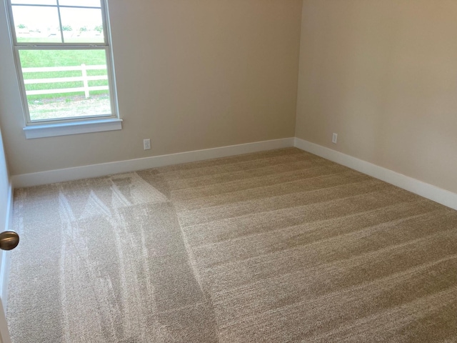 carpeted spare room featuring baseboards