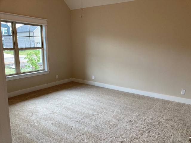 carpeted spare room with vaulted ceiling and baseboards