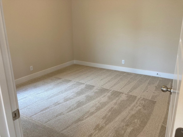 unfurnished room with light colored carpet and baseboards