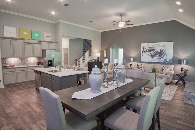 dining area with dark wood-style floors, crown molding, a ceiling fan, stairs, and arched walkways