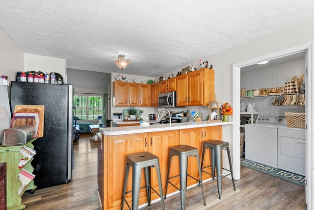204 Commanche Dr, Hohenwald, TN 38462 - kitchen with appliances with stainless steel finishes, light wood-style floors, light countertops, separate washer and dryer, and a peninsula