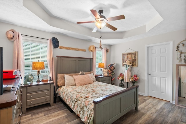 204 Commanche Dr, Hohenwald, TN 38462 - bedroom with light wood-style floors, a textured ceiling, a raised ceiling, and a ceiling fan