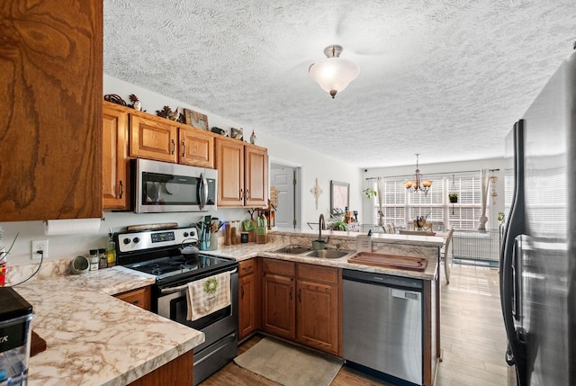 204 Commanche Dr, Hohenwald, TN 38462 - kitchen featuring appliances with stainless steel finishes, a sink, light countertops, a textured ceiling, and a peninsula