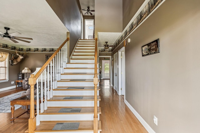 stairway featuring plenty of natural light, a ceiling fan, and baseboards