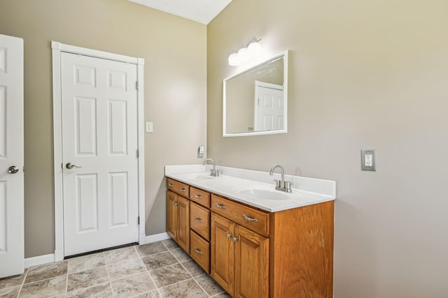 full bathroom featuring double vanity, baseboards, and a sink