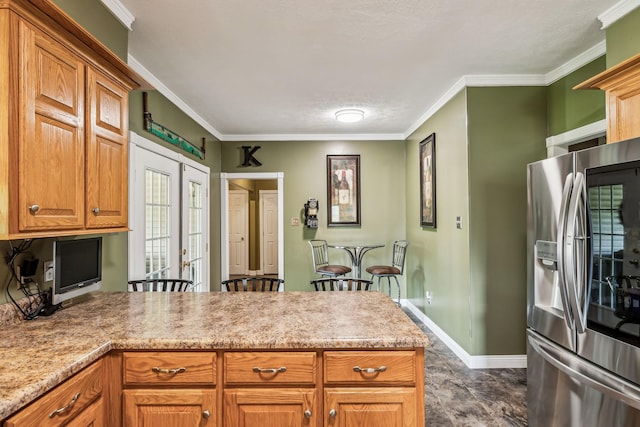 kitchen with ornamental molding, stainless steel fridge, a peninsula, and baseboards