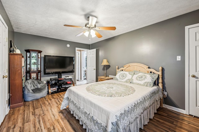 bedroom with a textured ceiling, ceiling fan, wood finished floors, and baseboards