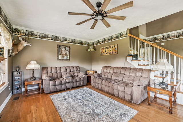 living area featuring visible vents, baseboards, wood-type flooring, a ceiling fan, and stairs