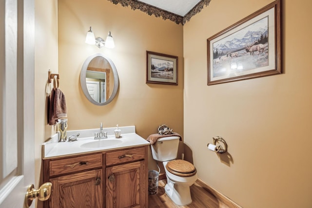 bathroom featuring baseboards, wood finished floors, toilet, and vanity